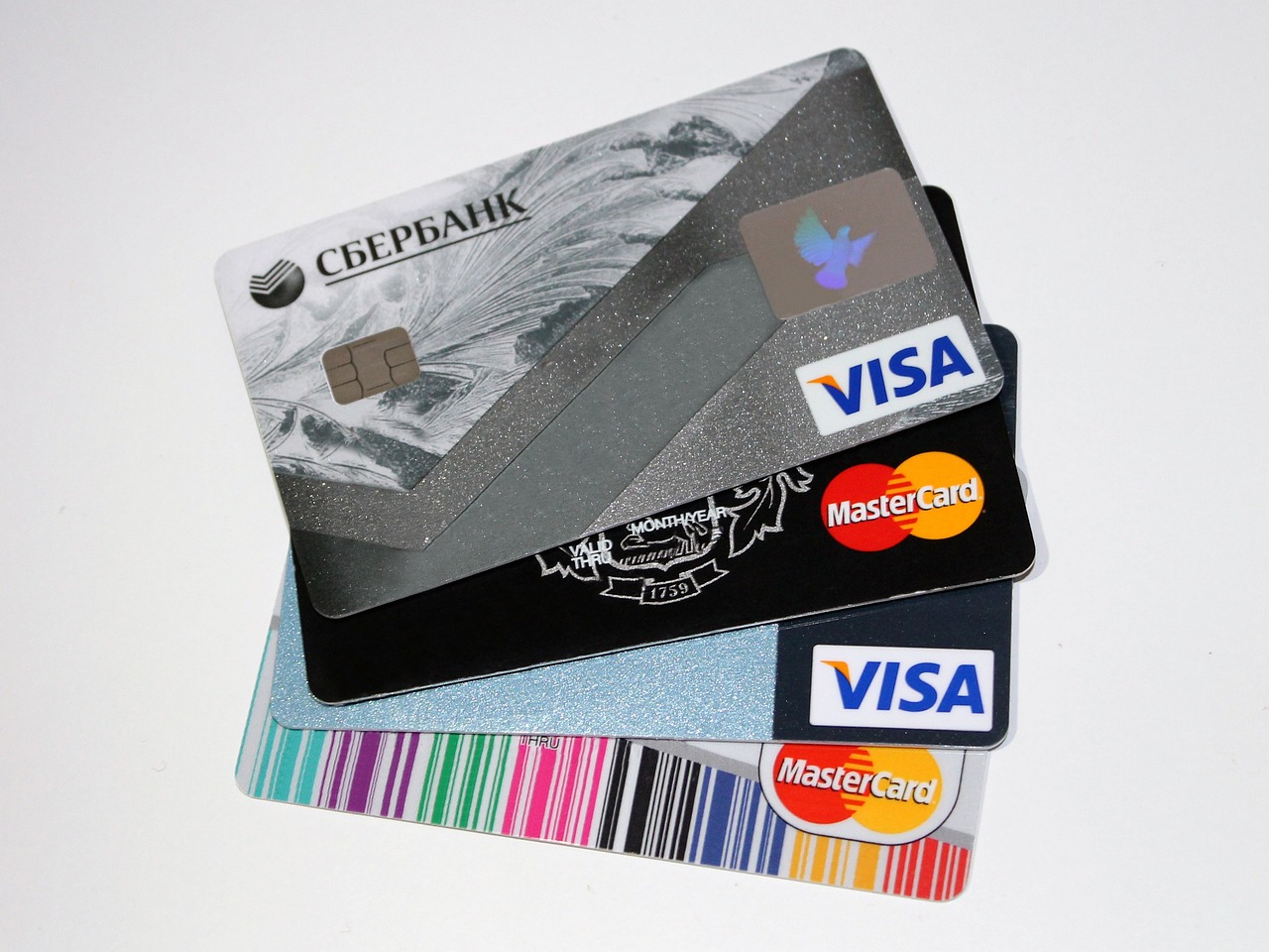 Four different credit cards laid on top of each other slightly fanned apart to show each card. Visa, then Mastercard, then Visa, then Mastercard.